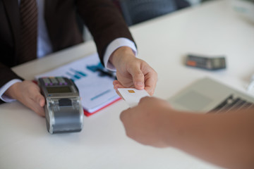 Businessman hand with credit card swipe through terminal