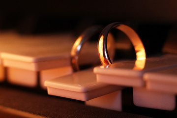 Wedding rings on piano so close, dark light