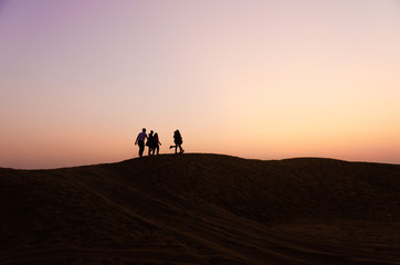 Fototapeta na wymiar silhouette of five friends in beautiful evening in desert