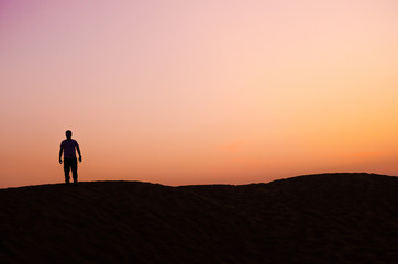 Fototapeta premium silhouette of lonely man in beautiful evening in desert