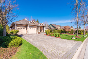 Beautiful exterior of newly built luxury home. Yard with green grass and walkway lead to designed...