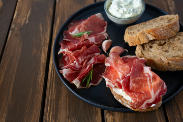 coppa di parma meat, cream cheese and ciabatta bread on wooden surface