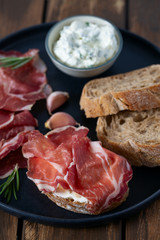 coppa di parma meat, cream cheese and ciabatta bread on wooden surface