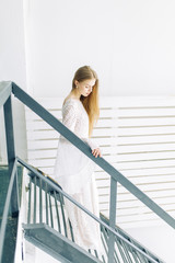  Wedding in the style of fine art. Beautiful bride in white interior Studio with stairs.