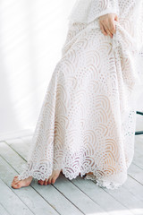 Beautiful bride sitting on a chair in the white Studio. Minimalistic wedding in European style.