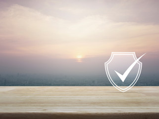 Security shield with check mark flat icon on wooden table over aerial view of cityscape at sunset, vintage style, Technology internet cyber security and anti virus concept