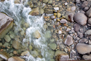 Water in the mountain raging river. Beautiful natural background of stones and water. Texture of clear water and fast river. Background to insert text. Tourism and travel.