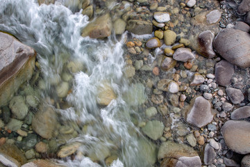 Water in the mountain raging river. Beautiful natural background of stones and water. Texture of clear water and fast river. Background to insert text. Tourism and travel.