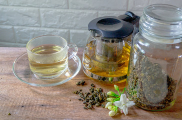 Hot tea in a glass and in a teapot With dried tea leaves in a glass bottle On the old wooden table