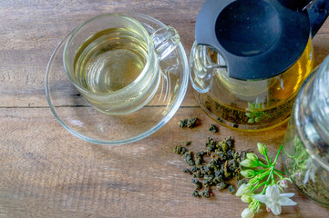 Hot tea in a glass and in a teapot With dried tea leaves in a glass bottle On the old wooden table