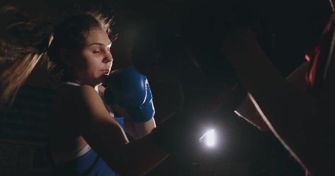 Female boxer punching a focus mitts with boxing gloves in a smoky gym