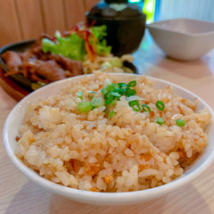 Garlic fried rice in a white ceramic bowl placed on a wooden table in a Japanese restaurant.