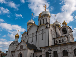 Golden domes of orthodox cathedral against bright blue sky and clouds at background