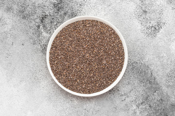 Chia seeds in a white saucer on a gray concrete background