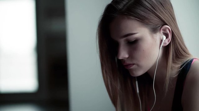 A portrait of young girl or woman with earphones in a gym. Slow motion.