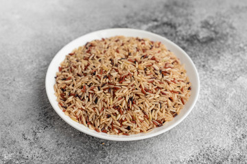 Rice in a white saucer on a gray concrete background