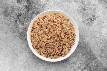 Rice in a white saucer on a gray concrete background