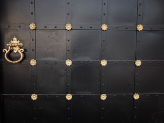Black forged gates with golden decorative elements, rivets and handles