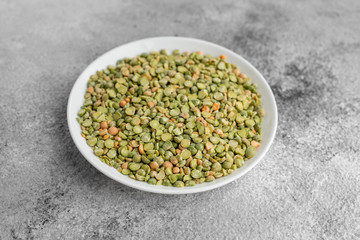 Peas in a white saucer on a gray concrete background