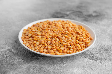 Peas in a white saucer on a gray concrete background