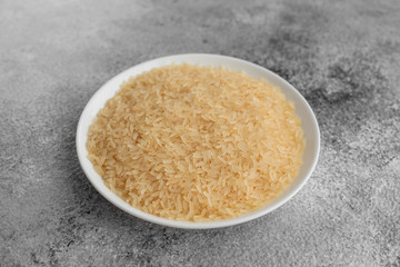Rice in a white saucer on a gray concrete background