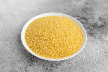 Couscous in a white saucer on a gray concrete background