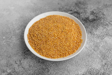 Wheat porridge in a white saucer on a gray concrete background