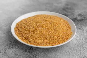 Wheat porridge in a white saucer on a gray concrete background