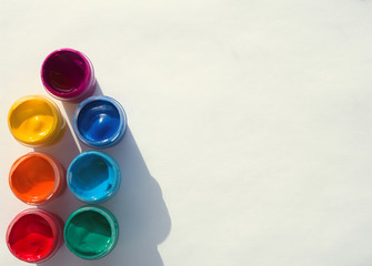 Colored gouache cans on a white background with a shadow, top view