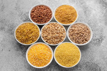Variations of porridges and bean in white saucers on a gray concrete background