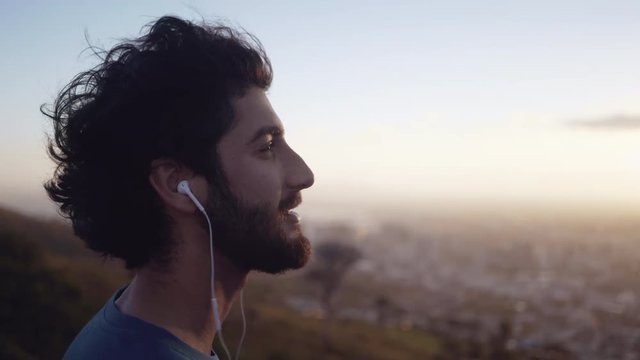 Close up shot a young white male in his sports clothes taking a break from doing exercise and admiring the landscape outdoors at sunrise