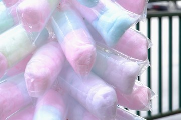 Close up a multicolored of cotton candy in a plastic packaging and a merchant selling on a street...