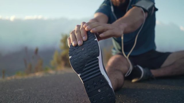 Young white brunette male in his workout clothes happily stretching his legs getting ready to do some exercise - Powered by Adobe