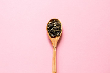 Biluochun. Chinese leaf green tea in a spoon on a pink background. Top view and copy space.