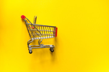 Top view and copy space. Shopping cart trolley on a yellow background.