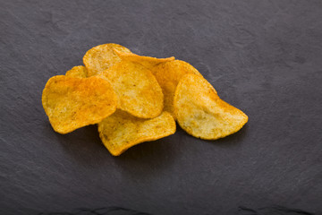 potato chips on a black stone background close-up