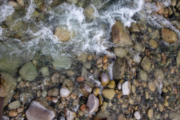 Water in the mountain raging river. Beautiful natural background of stones and water. Texture of clear water and fast river. Background to insert text. Tourism and travel.