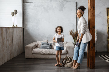 Naklejka premium Happy loving family. Young mother and her daughter girl play in kids room. Funny mom and lovely child are having fun with tablet.