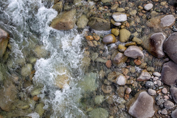 Water in the mountain raging river. Beautiful natural background of stones and water. Texture of clear water and fast river. Background to insert text. Tourism and travel.