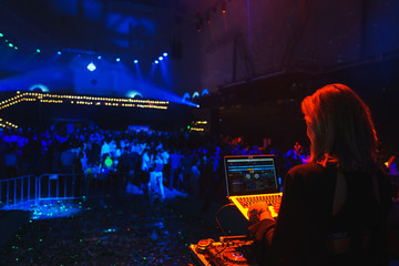 Stylish girl DJ at the music console during a performance in a nightclub. 