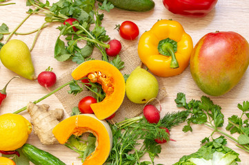 vegetables fruits and greens on wooden background. pear, hot red pepper, pumpkin, persimmon, mango, cucumber, radish, lemon, Apple, dill, parsley, cabbage