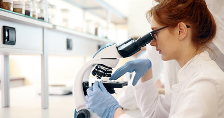 Young scientist looking through microscope in laboratory