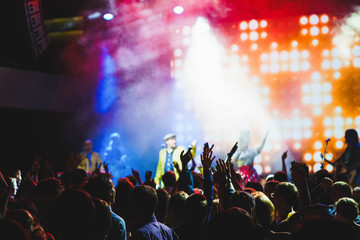 Crowd of young people with their hands up during the performance of your favorite musical group