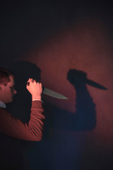 Young man in brown sweater holding knife.