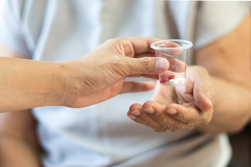 Caregiver or nurse give medicine to happy elderly senior patient in hospice care centre or hospital. Caretaker taking care elderly female in nursing home. Geriatric doctor or geriatrician concept. 