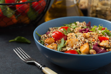 Salad with quinoa, avocado and chicken. Front view. Served in a blue bowl.