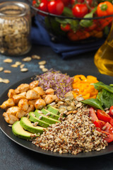 Salad with quinoa, avocado and chicken. Front view. Served on a black plate.