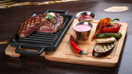Fototapeta na wymiar Rib eye steak on wooden tray with grilled vegetables