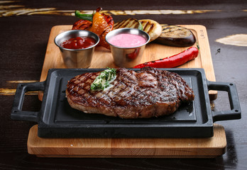 Rib eye steak on wooden tray with grilled vegetables