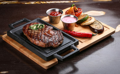 Rib eye steak on wooden tray with grilled vegetables